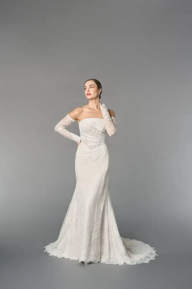 model is wearing a strapless fit and flare lace bridal gown with off the shoulder detachable gauntlet sleeves