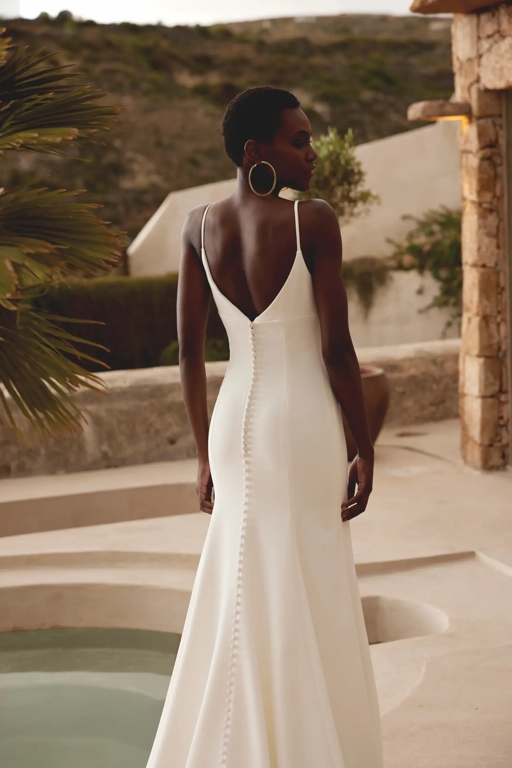 Model is wearing a crepe fit and flare wedding dress with 3D floral details