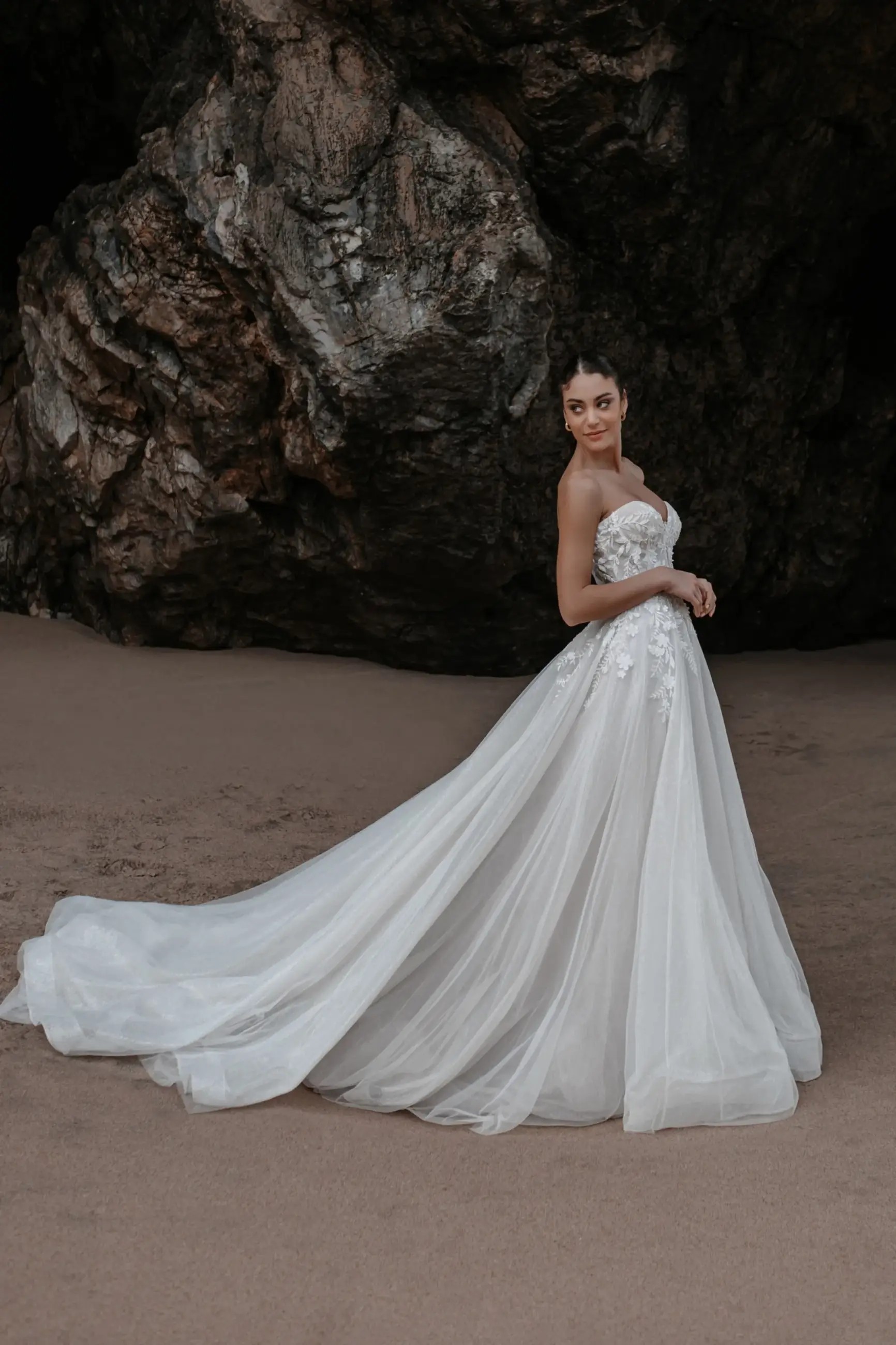 Model is wearing an a-line wedding dress with a tulle skirt and strapless sweetheart bodice