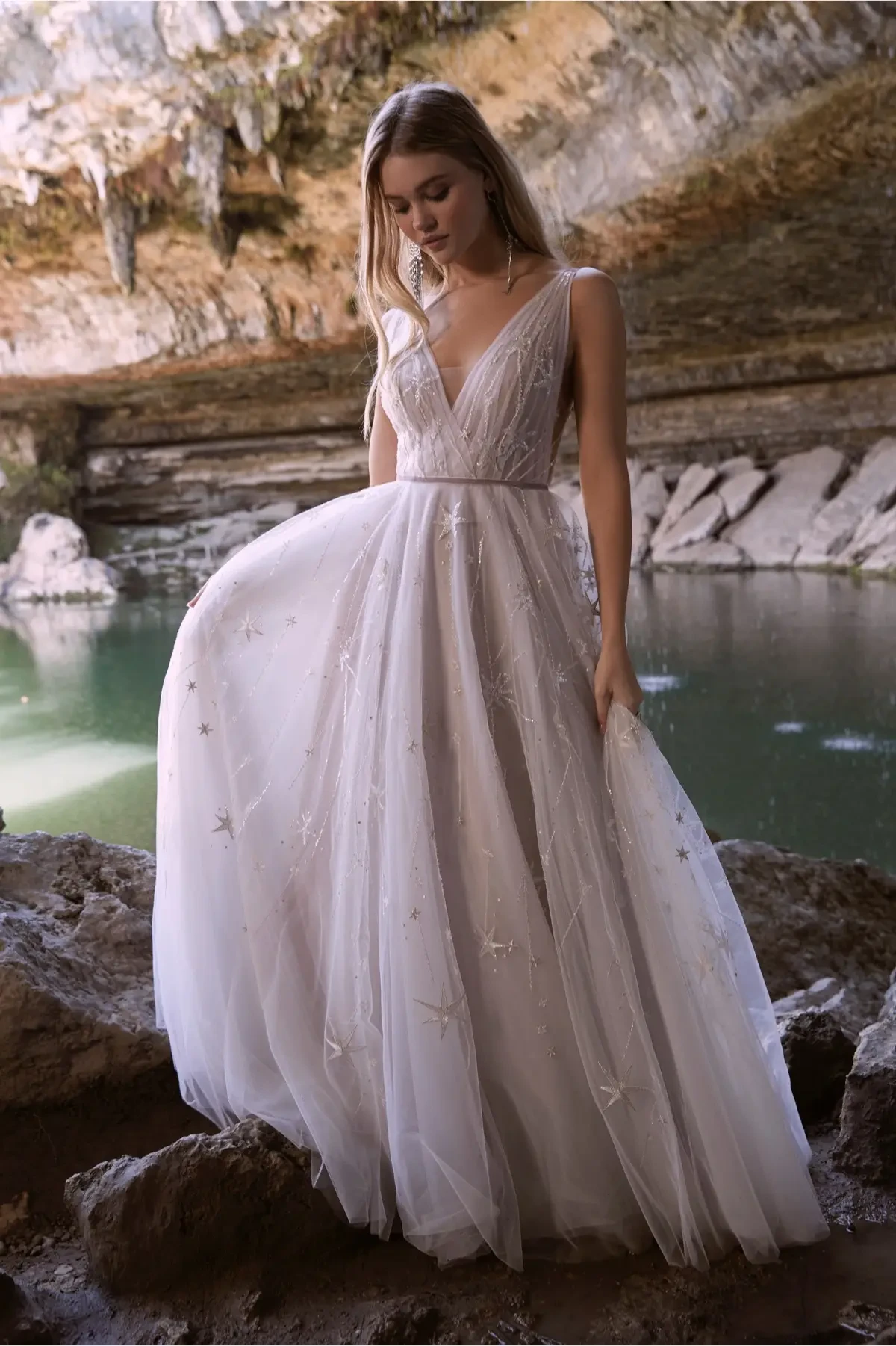 model is wearing a sleeveless open back a-line wedding dress with tulle