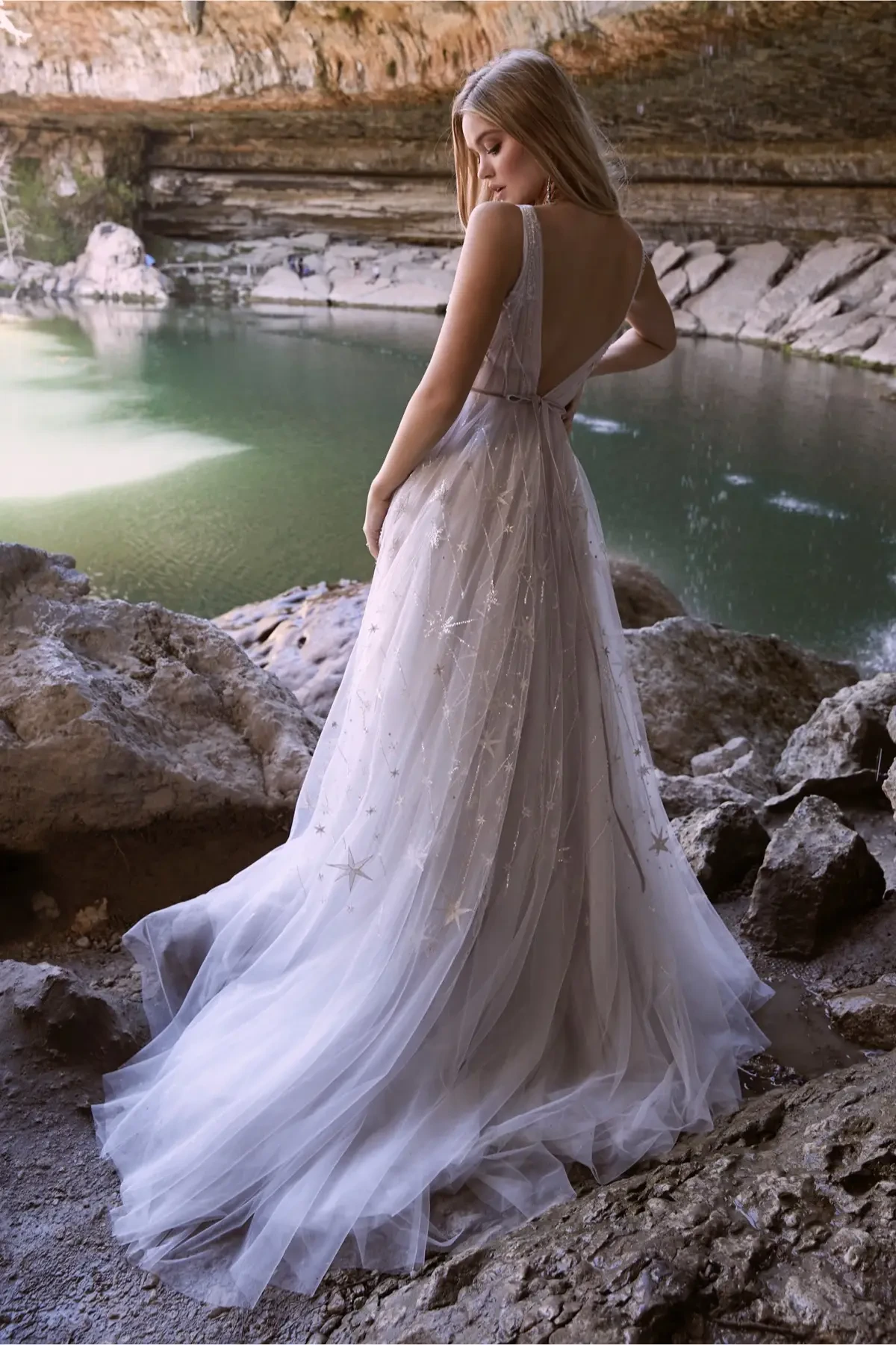 model is wearing a sleeveless open back a-line wedding dress with tulle